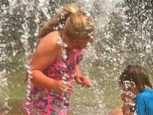 Two children joyfully playing in a fountain